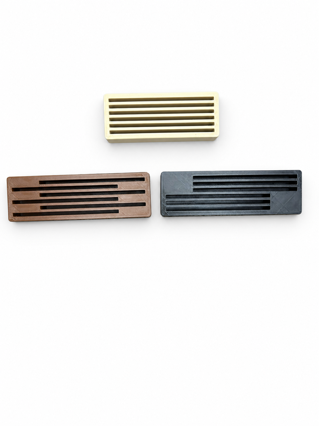 Empty coaster holders on a white background: beige Centered at top, brown Staggered at lower left, and black Split at lower right.