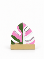 Pink, green and white Mini Monstera coasters in a beige centered holder on a white background.