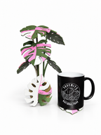 Pink, white and green Monstera coaster display with a mug on a leaf coaster, photographed on a white background.